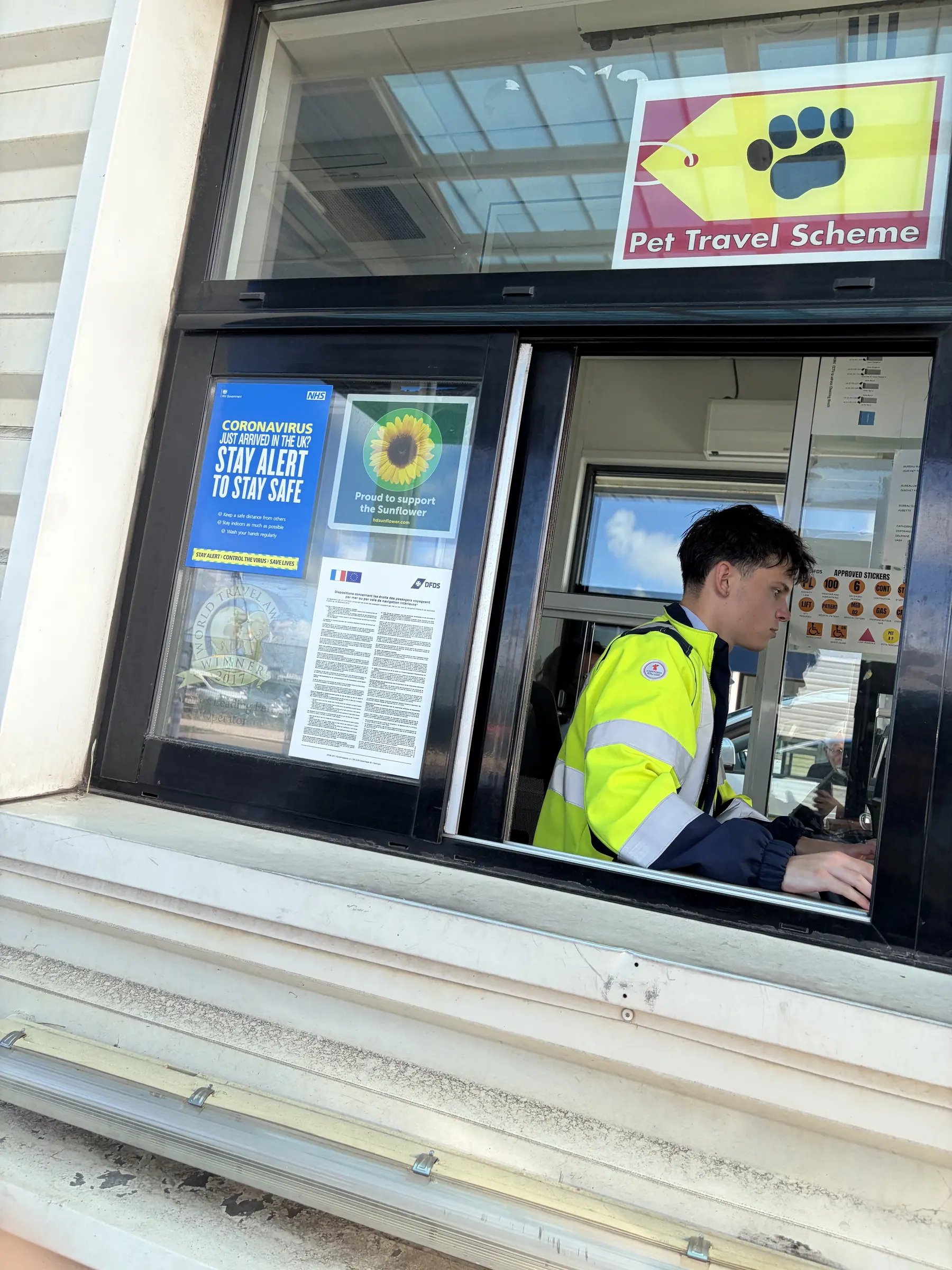 DFDS agent in the check-in booth, with the Pet Travel Scheme sign